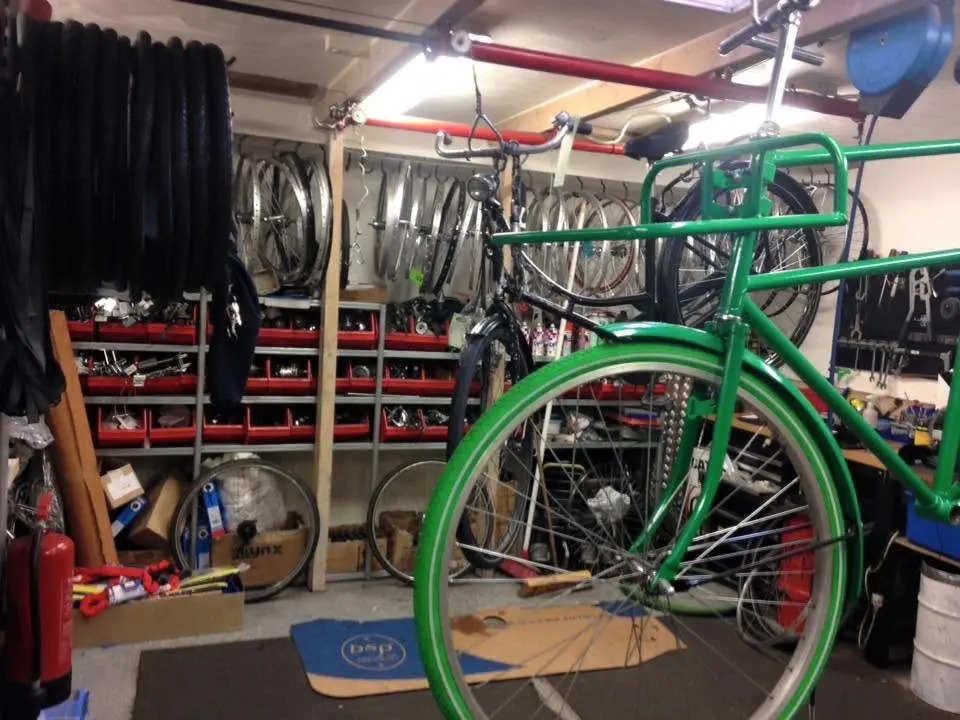 De werkplaats: een wand met banden, laden met onderdelen en een fiets in de montagestandaard.