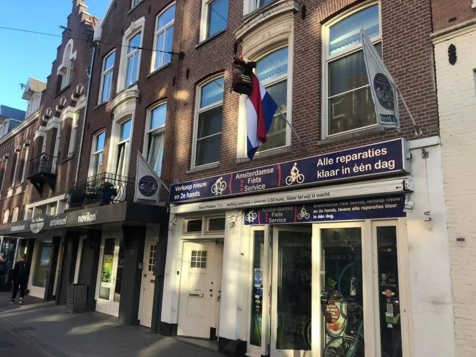 De winkel aan de Amstelveenseweg 144-H: een blauwe gevel met de tekst Amsterdamse Fiets Service en Alle reparaties klaar in één dag, fietsen voor de deur.